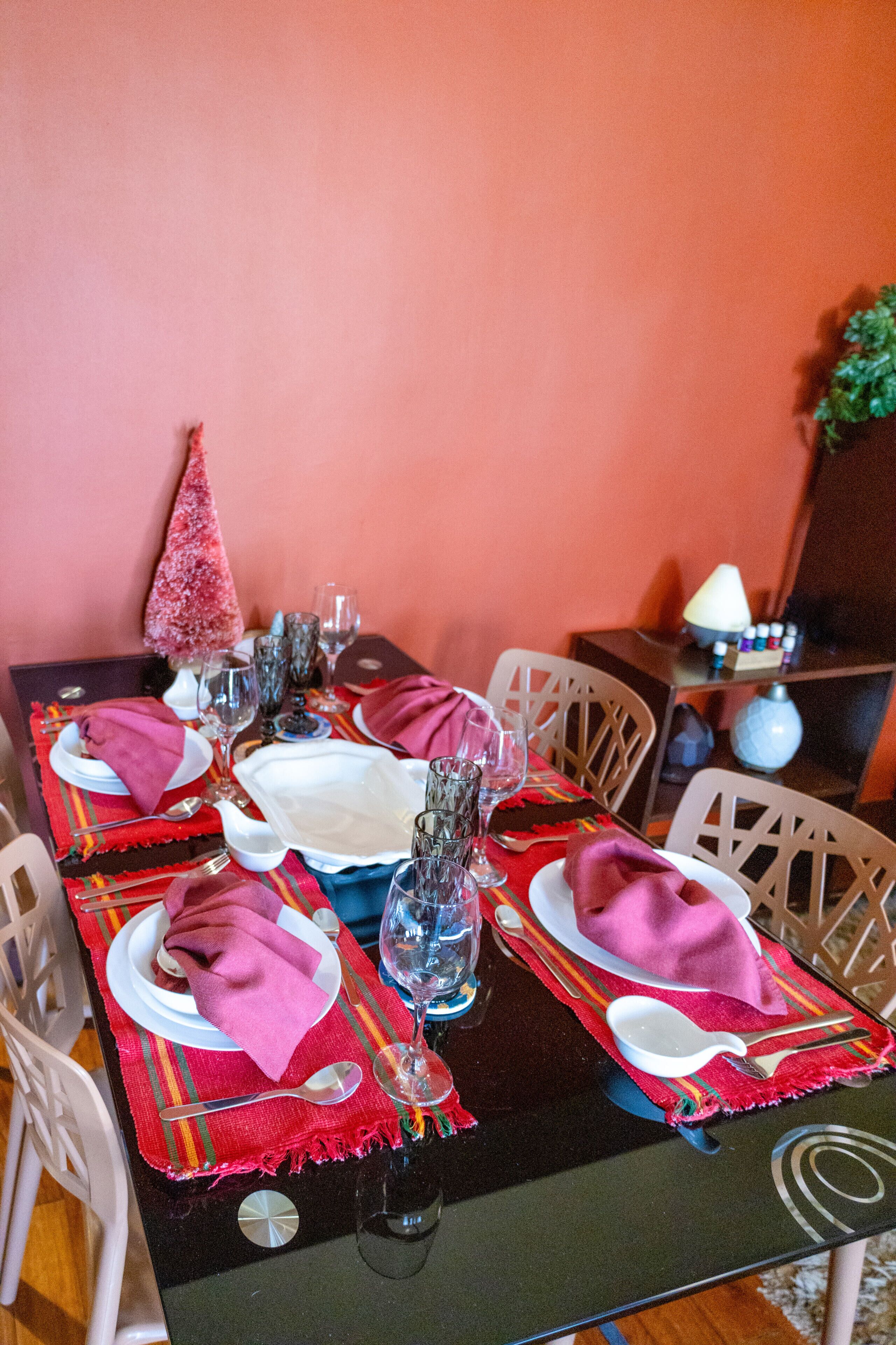 A dining table set with plates, glasses, and napkins, surrounded by chairs.