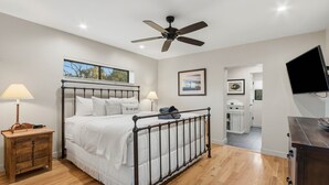 A bedroom with a bed, bedside tables, a ceiling fan, a TV, and a view of the outdoors. - 3BR Uptown Sedona retreat with red rock views, hot tub, and patio (Sedona)