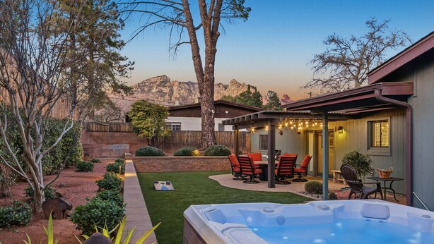 A backyard with a hot tub, patio furniture, and a view of mountains. - 3BR Uptown Sedona retreat with red rock views, hot tub, and patio (Sedona)