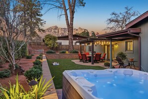 A backyard with a hot tub, patio furniture, and a view of mountains. - 3BR Uptown Sedona retreat with red rock views, hot tub, and patio (Sedona)
