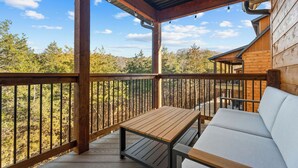 Um deck de madeira com mesa e banco, com vista para uma área arborizada.