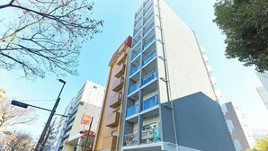 A multi-story building with balconies, a visible storefront, and a clear sky. - VORT Yamabukicho Residence (Tokyo)