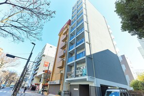 A multi-story building with balconies, a visible storefront, and a clear sky. - VORT Yamabukicho Residence (Tokyo)