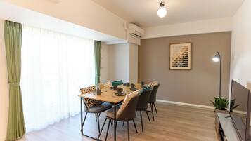 A dining area with a wooden table, chairs, and a TV stand.