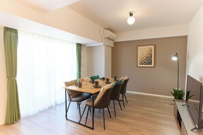 A dining area with a wooden table, chairs, and a TV stand. - VORT Yamabukicho Residence (Tokyo)