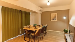 A dining area with a wooden table, chairs, and a green curtain. - VORT Yamabukicho Residence (Tokyo)