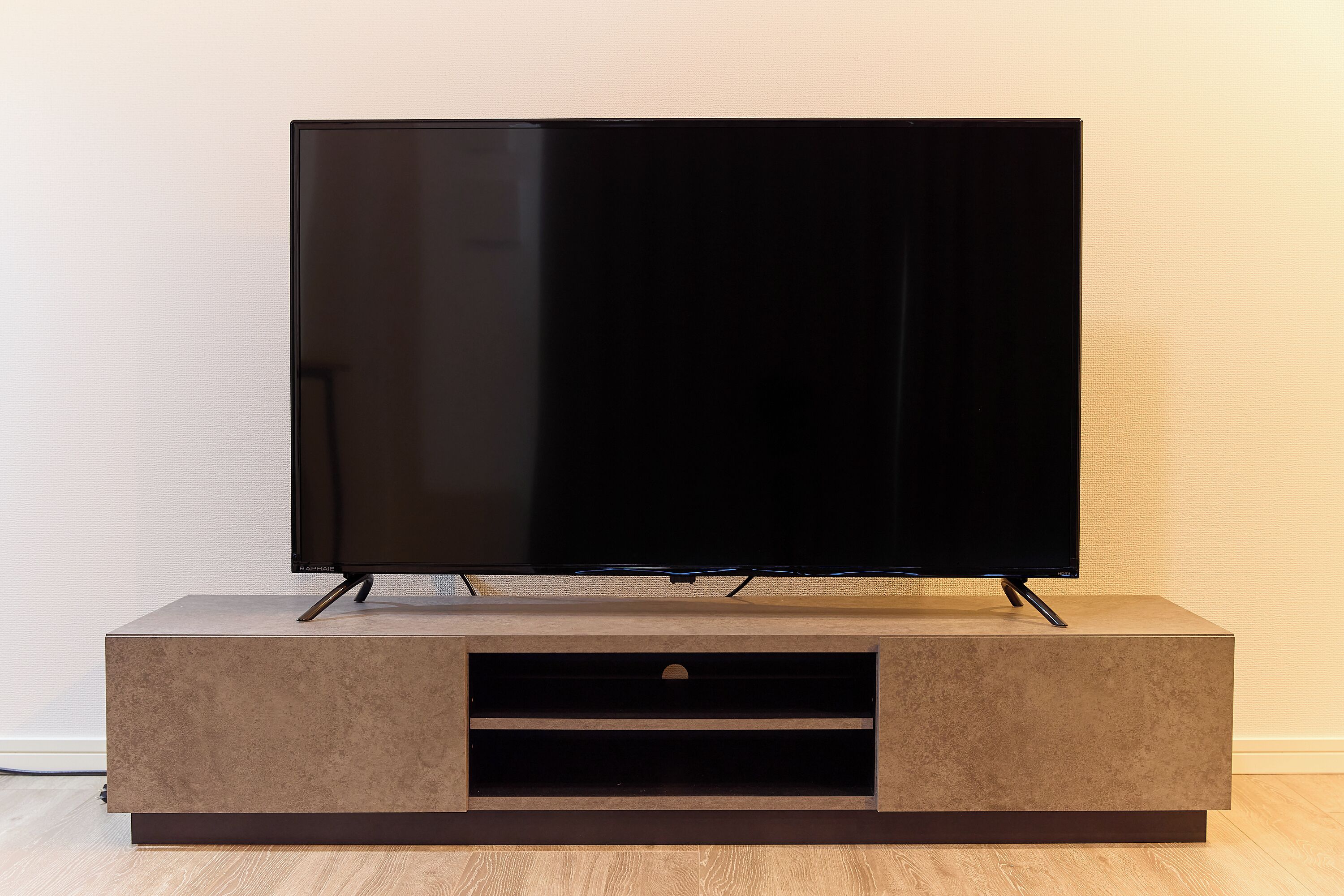 A flat-screen TV on a wooden TV stand with a drawer below.