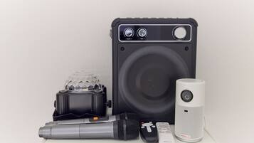 A portable speaker, a microphone, a remote control, and a speaker box with a large speaker and control knobs.