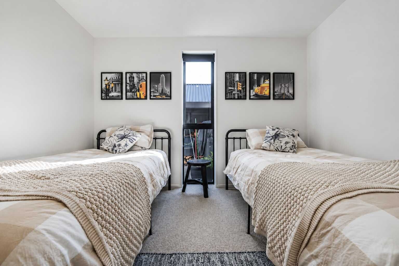 A bedroom with two beds, a small table, and a window.