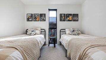 A bedroom with two beds, a small table, and a window.