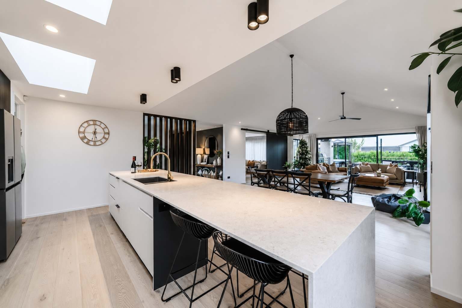 Une cuisine moderne dotée d’un îlot central, de tabourets de bar et d’un coin repas comprenant un canapé et une table basse.