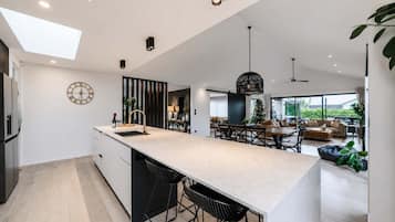 Une cuisine moderne dotée d’un îlot central, de tabourets de bar et d’un coin repas comprenant un canapé et une table basse.