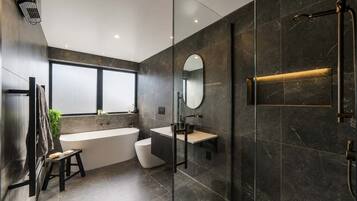 A modern bathroom with a freestanding bathtub, a glass-enclosed shower, and a large mirror.