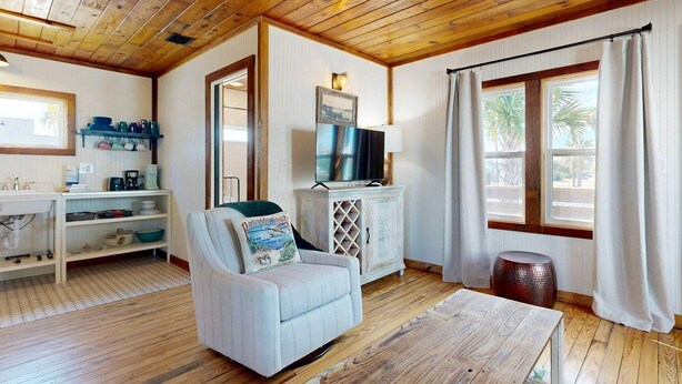 Una sala de estar acogedora con un sofá blanco, un televisor y un techo de madera.