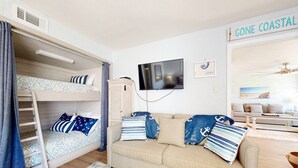 Een knus vertrek met een stapelbed, een slaapbank en een televisie.