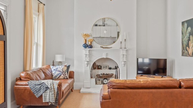 A living room with a fireplace, leather sofas, a TV, and a chandelier. - The Countess Central Heritage in Launceston (Launceston)