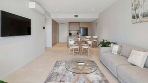 Una sala moderna con una mesa de centro de vidrio, un sofá y un comedor con sillas.