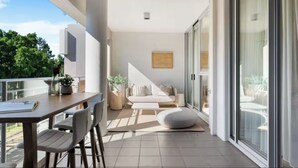 En moderne balkon med spiseplads, sofa og stort vindue.