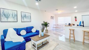 Ein modernes Wohnzimmer mit einem blauen Sofa, einem Couchtisch und einer Küchenzeile mit einer Bar.