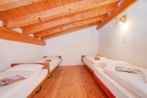 Ein kleiner, gemütlicher Raum mit zwei Holzbettgestellen, einer Holzbalkendecke und einer weißen Wand.