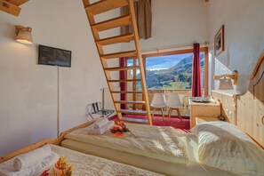 Ein Schlafzimmer mit einer Holzleiter, einem Fernseher und Blick auf eine Berglandschaft.