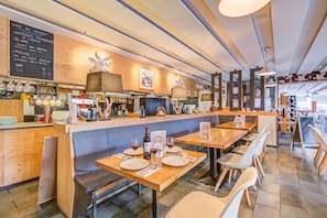 Ein Restaurantinnenraum mit Holztischen und -bänken, einer Bar und einer Tafel mit der Speisekarte.