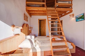 Eine Holztreppe führt zu einem Schlafzimmer auf dem Dachboden mit einem Bett und einem Schreibtisch.