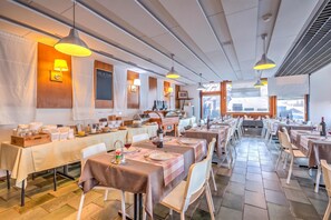 Un restaurante con varias mesas de comedor, cada una con platos, cubiertos y vasos.