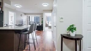 A modern kitchen with a bar area, a dining space with a view, and a small table with a plant.