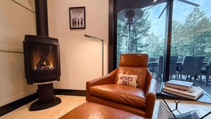 Une pièce chaleureuse avec un canapé en cuir, une cheminée et une vue sur l’extérieur.