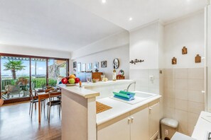 Eine moderne Küche mit Essbereich, Meerblick und einem Badezimmer mit Toilette und Waschbecken.