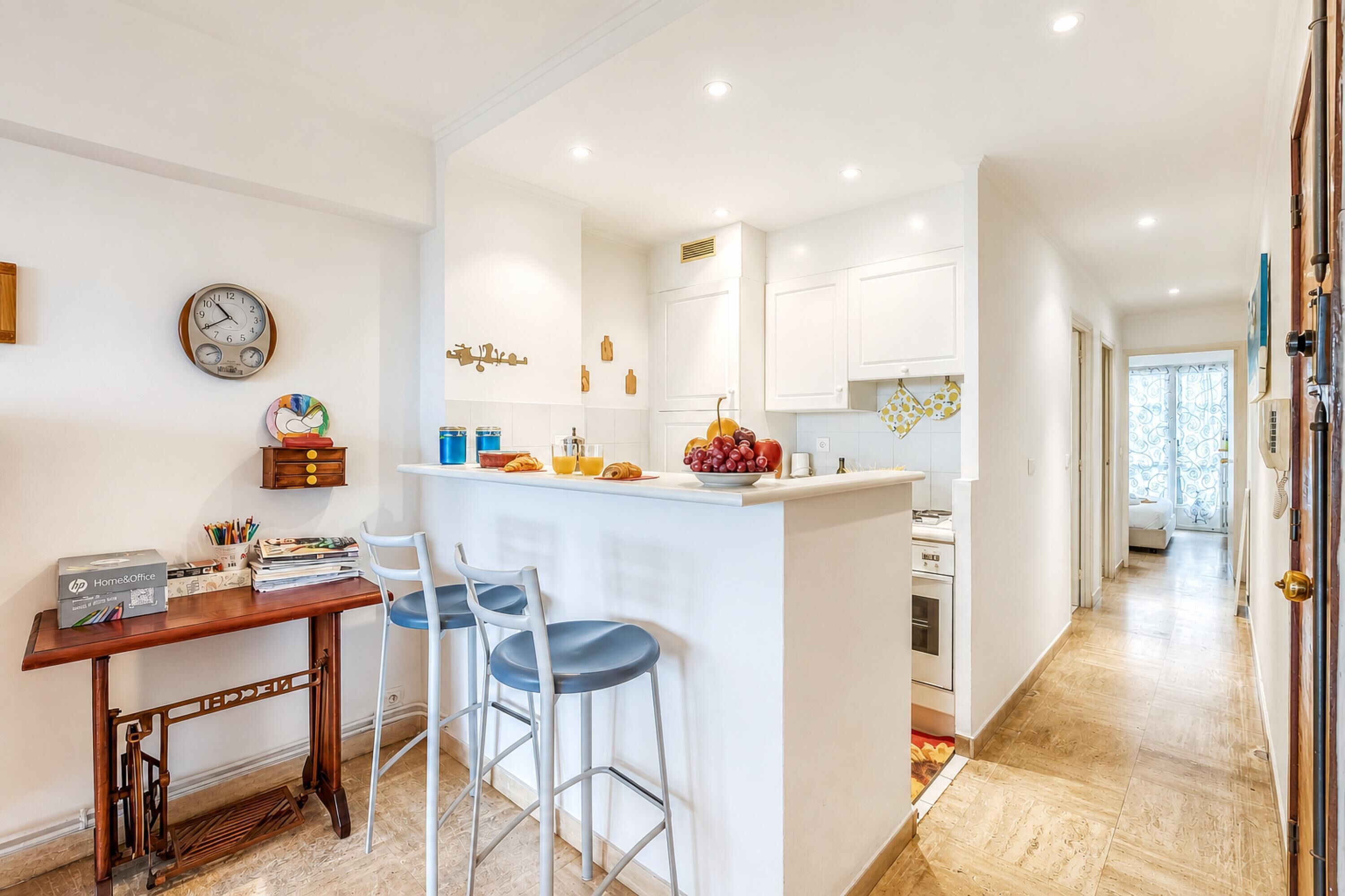 A modern kitchen with white cabinetry, a central island, and a dining area with a wooden table and two bar stools.