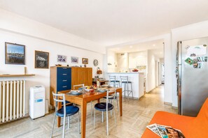 Eine moderne Küche mit Essbereich, einem Kühlschrank und einem Wohnzimmer mit einer Couch.