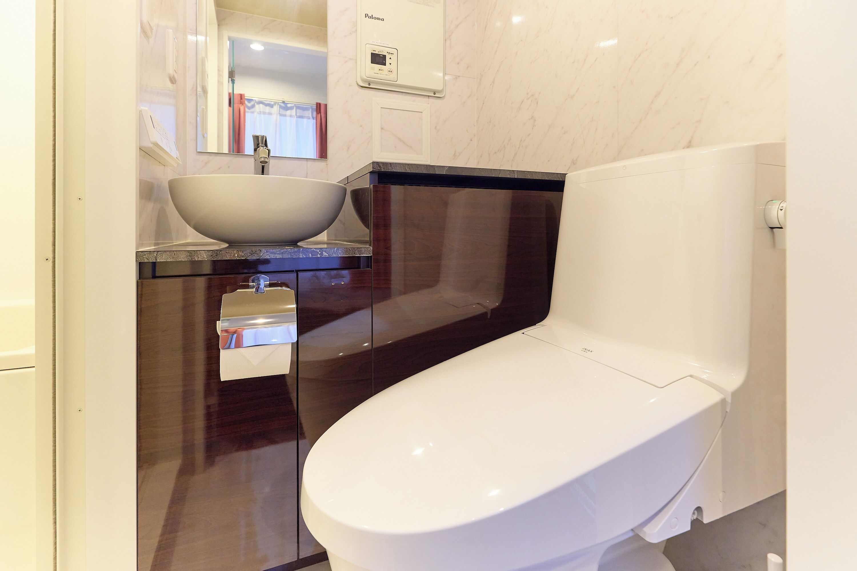 Een moderne badkamer met een wit toilet, een groot wit wastafel en een spiegel boven de wastafel.