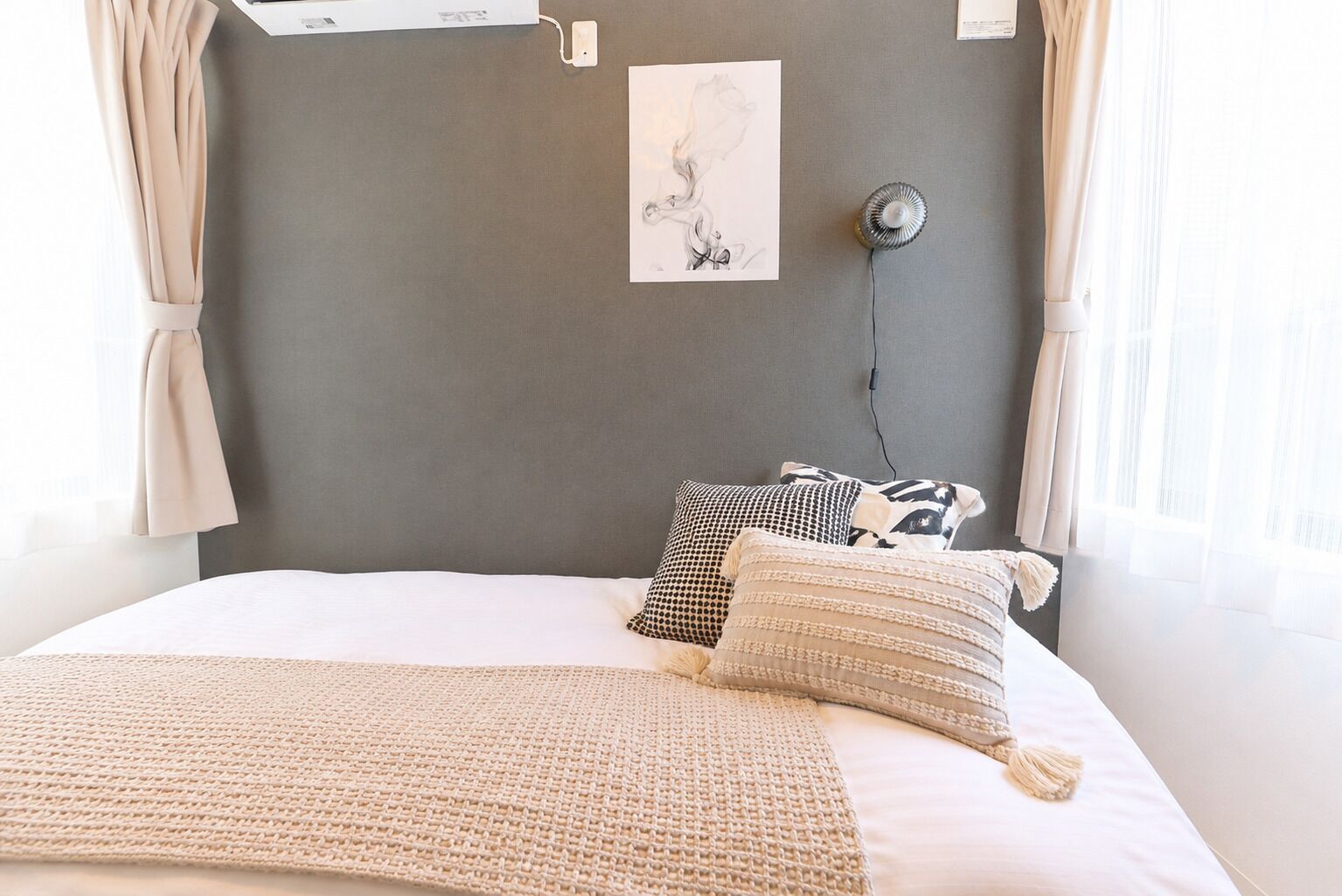 Un dormitorio con una cama, una lámpara de pared y una obra de arte enmarcada.