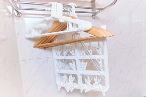 Ein Badezimmer mit weißem Marmorboden, einem Metallhandtuchhalter und einem weißen Kunststofftrockner mit Holz- und weißen Wäscheklammern.