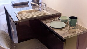 Una cucina con un lavandino, un bollitore, una ciotola e una tazza sul bancone.