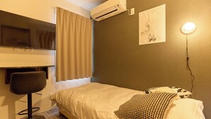 Camera d'albergo con un letto, una sedia, un condizionatore d'aria, una lampada a parete e un quadro.