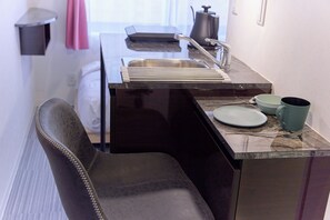 A compact kitchen with a sink, a kettle, and a chair. - HJ-PLACE Shibuya Hatagaya (Tokyo)