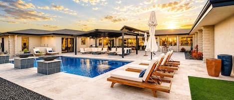 A modern outdoor pool area with lounge chairs and a covered patio.