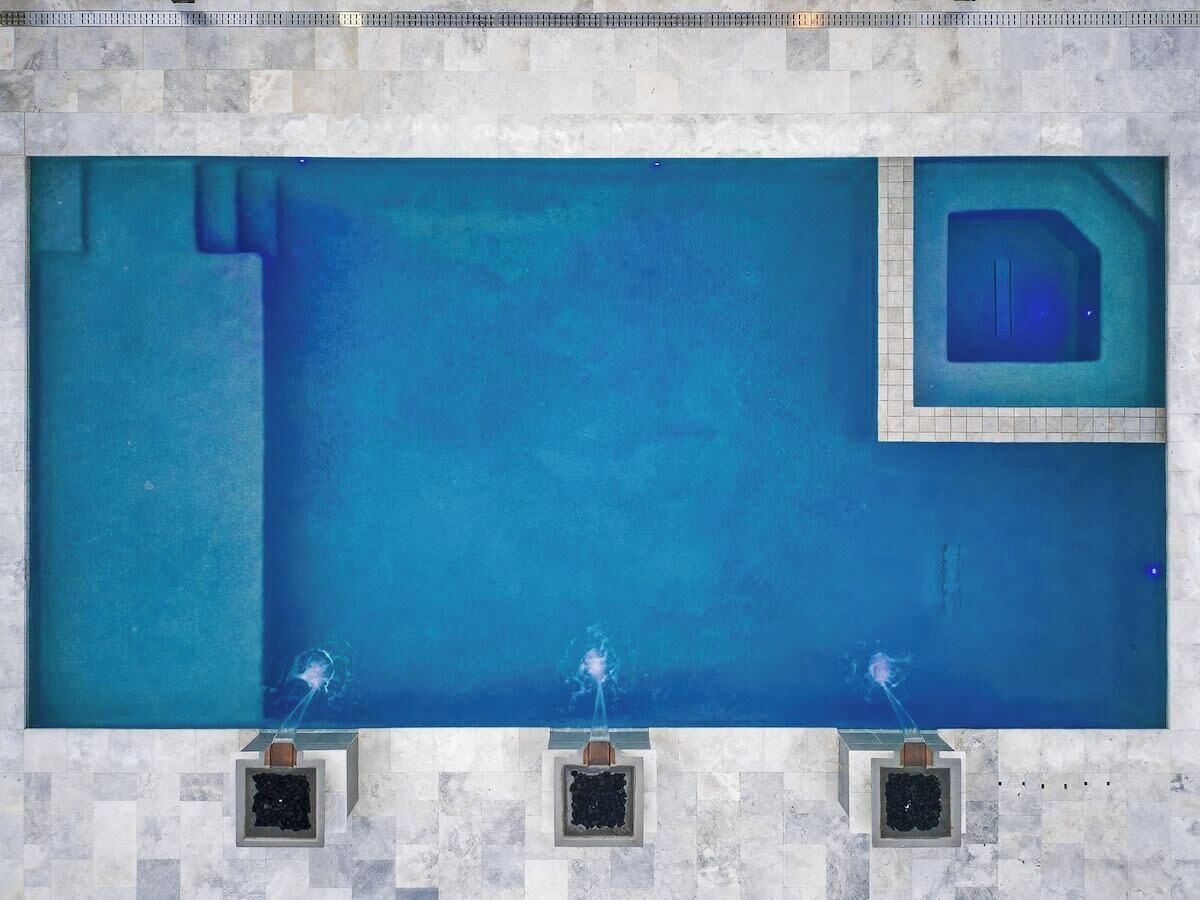 A rectangular swimming pool with three water jets, tiled walls, and a small window.