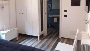 A bedroom with a bed, a wardrobe, a desk, and a chair. There is a door leading to another room. - Classic family room for 2 to 4 people (Camerota)