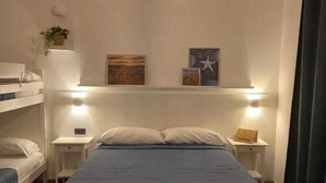 A bedroom with a bed, bedside tables, a hanging light, and artwork on the wall. - Classic family room for 2 to 4 people (Camerota)