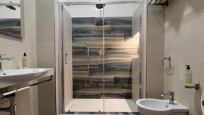A modern bathroom with a glass-enclosed shower, two sinks, and a toilet. - Sea view room with private terrace (Camerota)