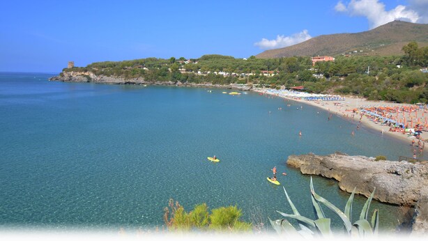 A coastal beach with clear waters, a rocky shoreline, and a mountainous backdrop. - Sea view room with private terrace (Camerota)