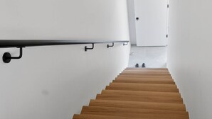 Una scala moderna con gradini in legno che conduce a una porta bianca.