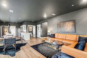 A modern living room with a sofa, coffee table, and dining area. - Sunset-Expansive Patio & Hot Tub-Mins to Broadway (Nashville)