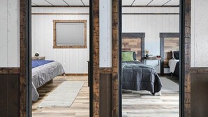 Un dormitorio con cama, mesita de noche, ventana y suelo de madera.
