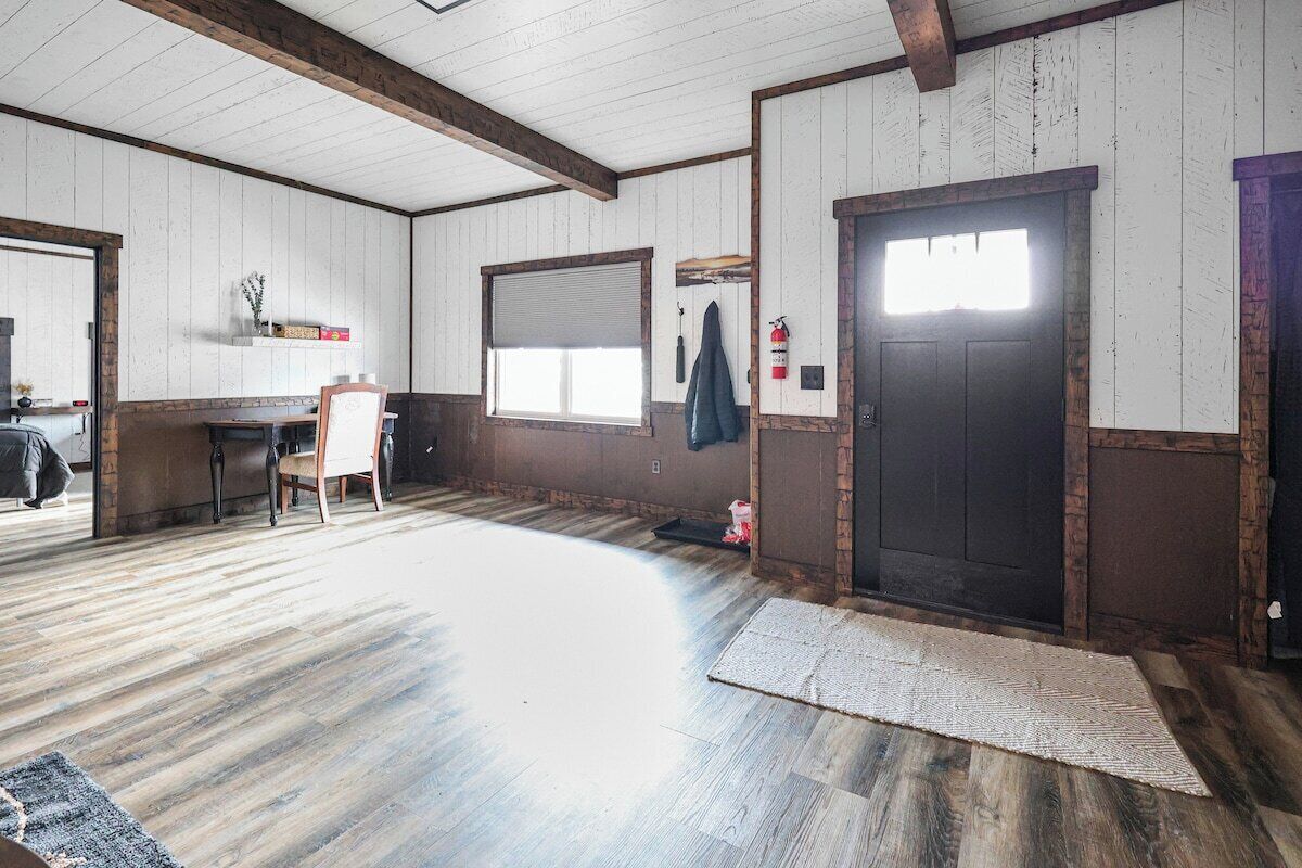 Une pièce spacieuse avec un plancher en bois, une grande porte et une fenêtre.