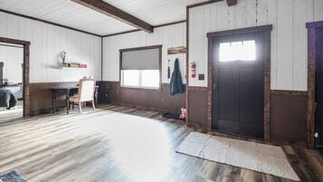 Une pièce spacieuse avec un plancher en bois, une grande porte et une fenêtre.